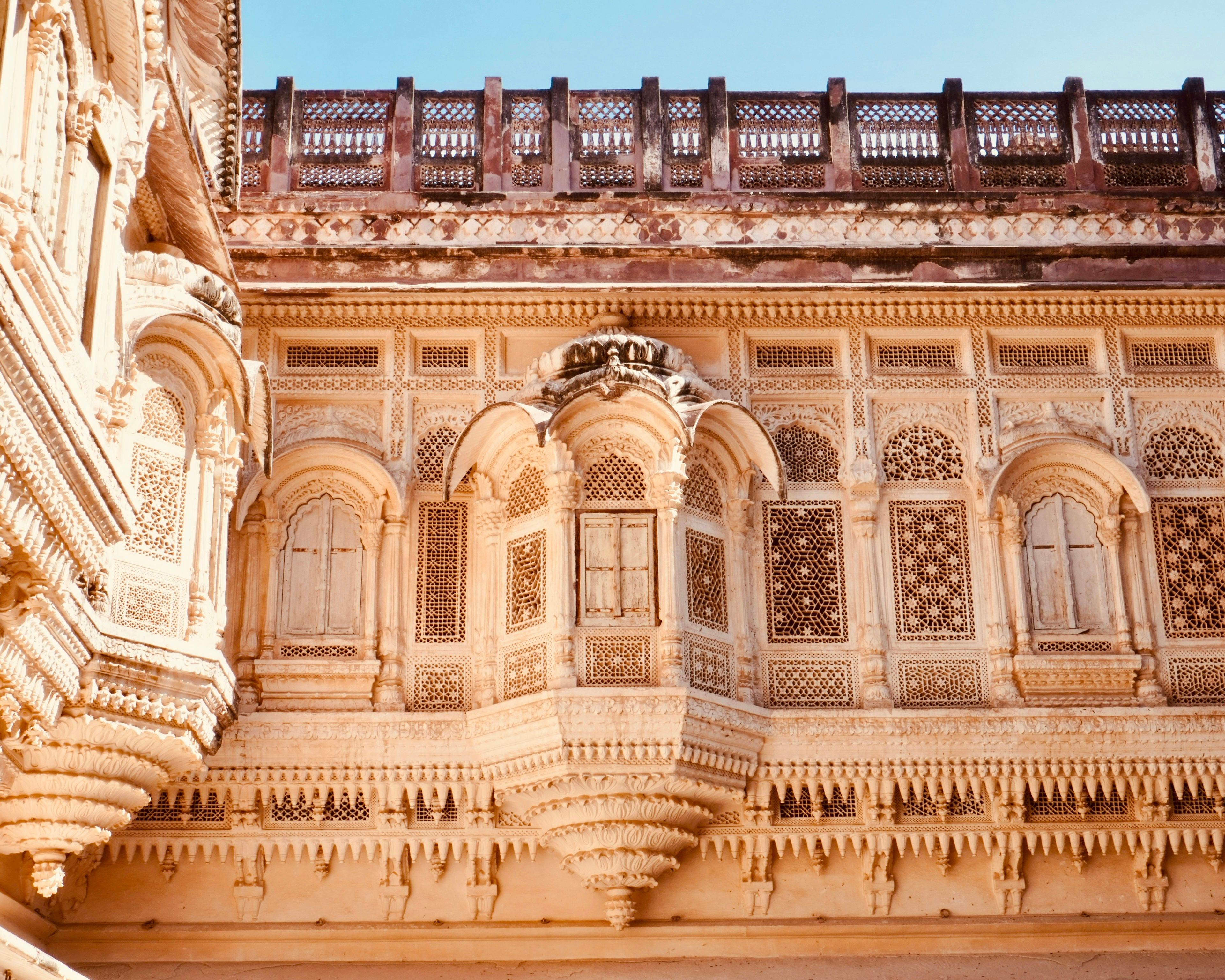 Sunlit carved sandstone balconies and lattice windows inside Mehrangarh Fort in Jodhpur