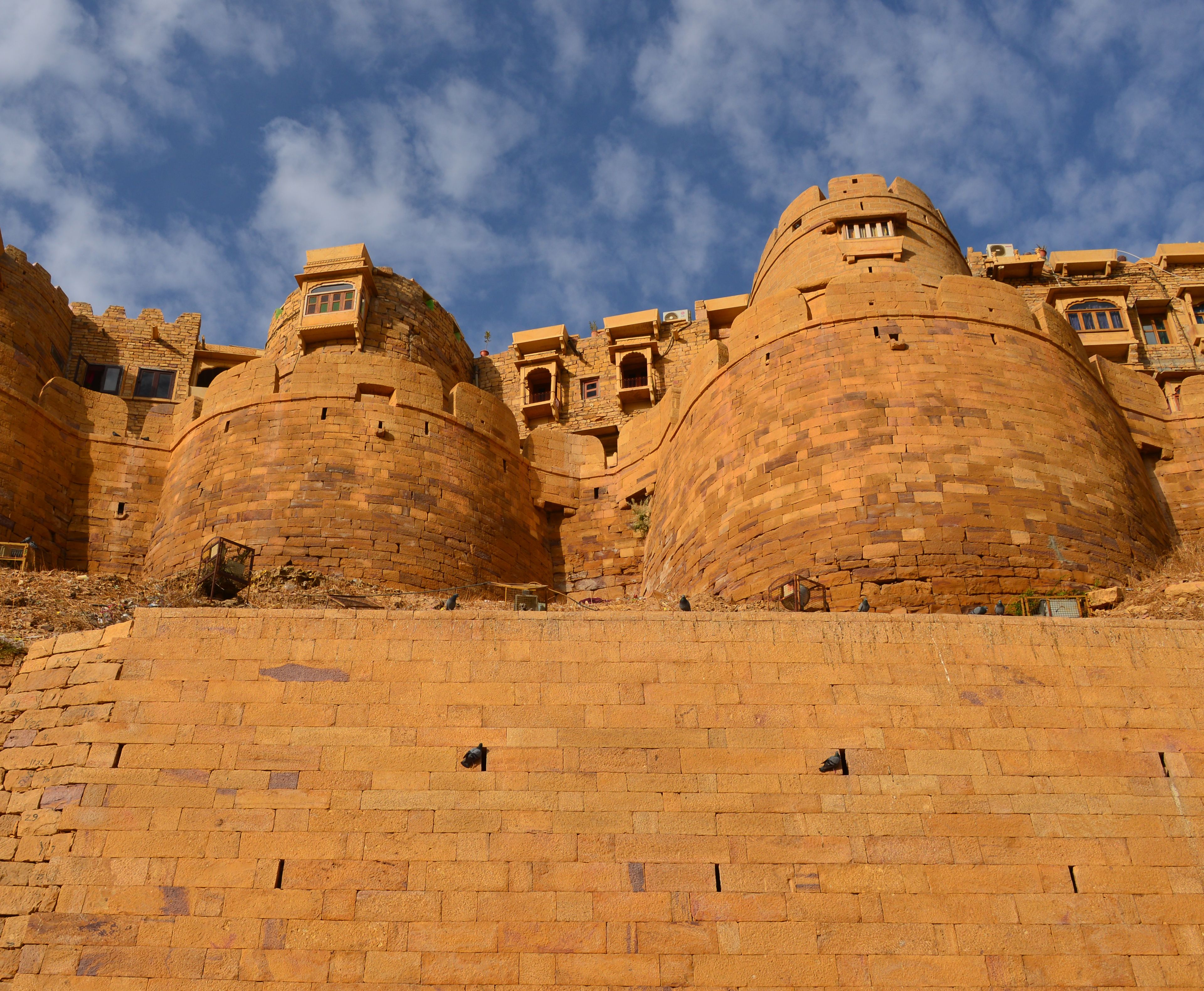 Golden sandstone bastions of Jaisalmer Fort beneath a blue, cloud-streaked sky
