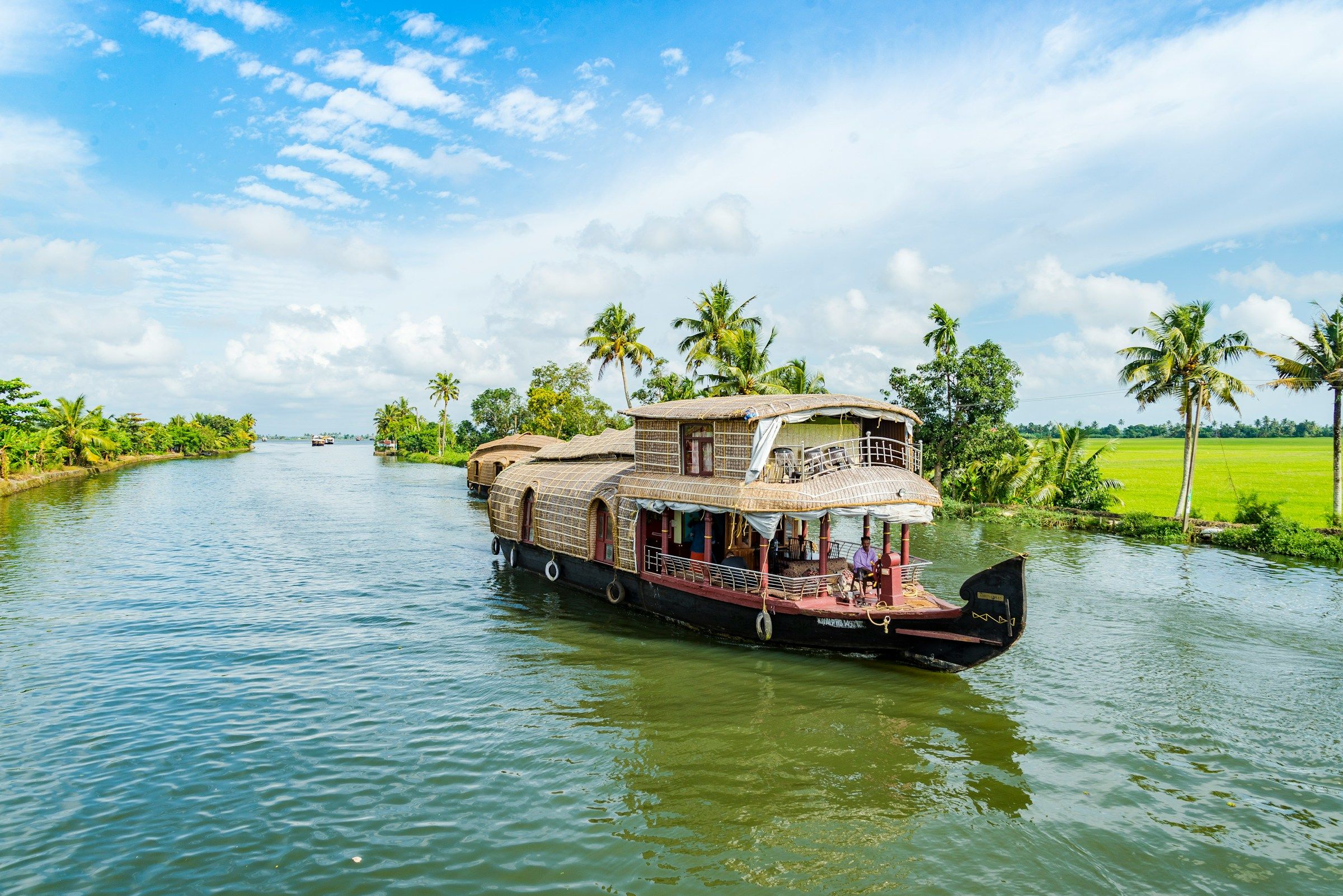 A traditional houseboat on a palm-lined waterway in Alappuzha, Kerala