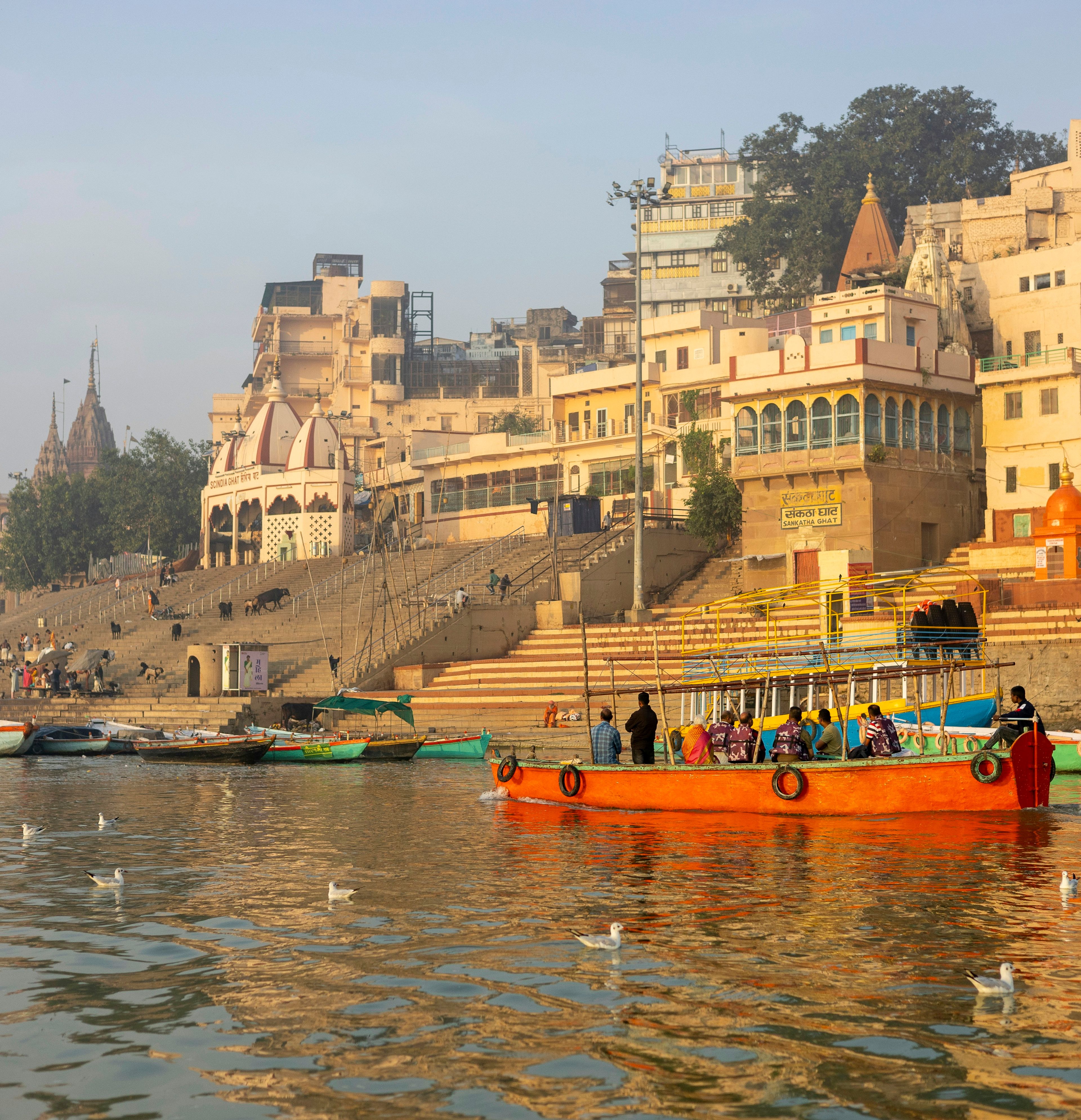 Warm light on Varanasi’s riverfront palaces and ghats, with a wooden boat on the Ganges