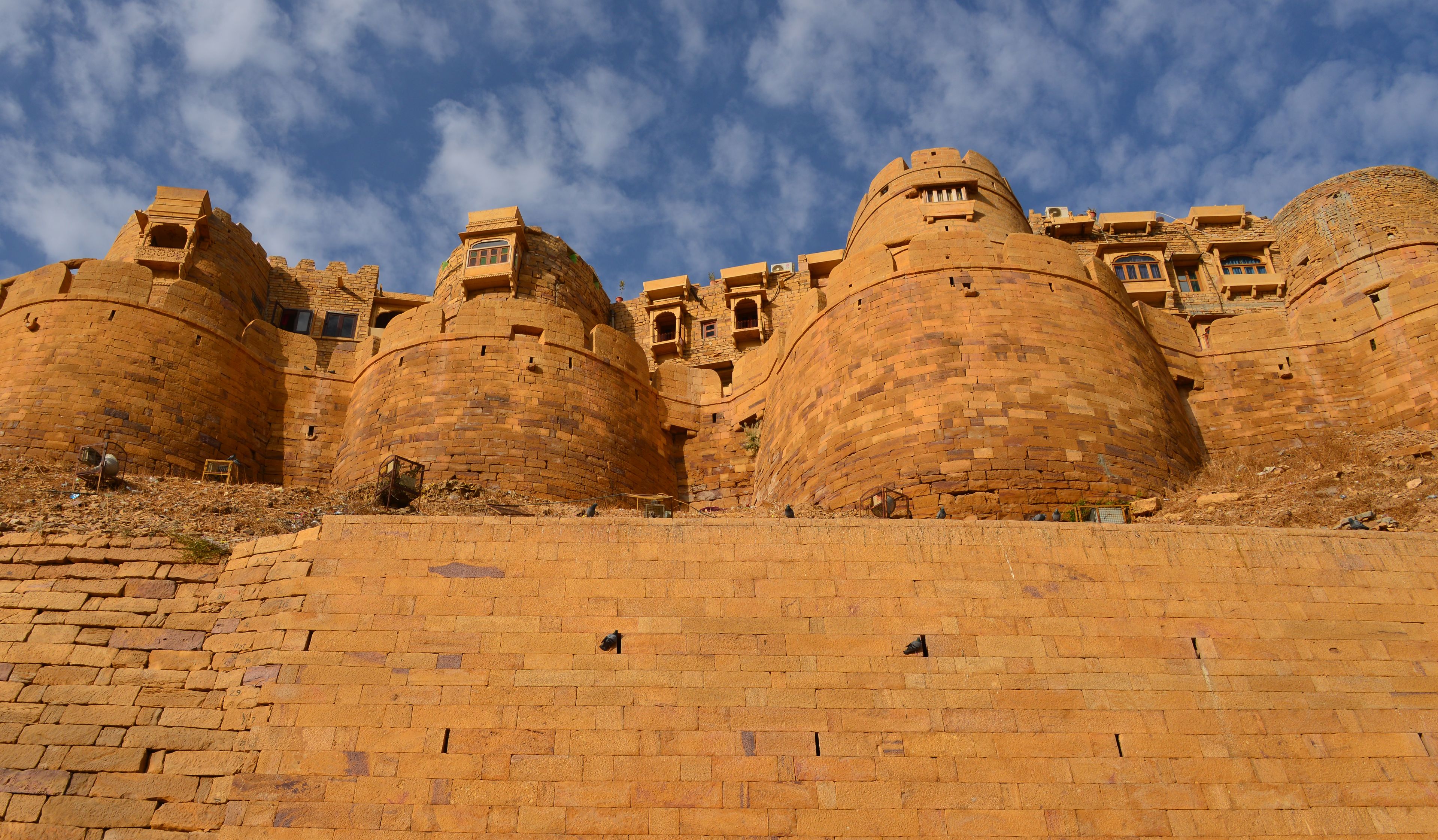Golden sandstone bastions of Jaisalmer Fort beneath a blue, cloud-streaked sky