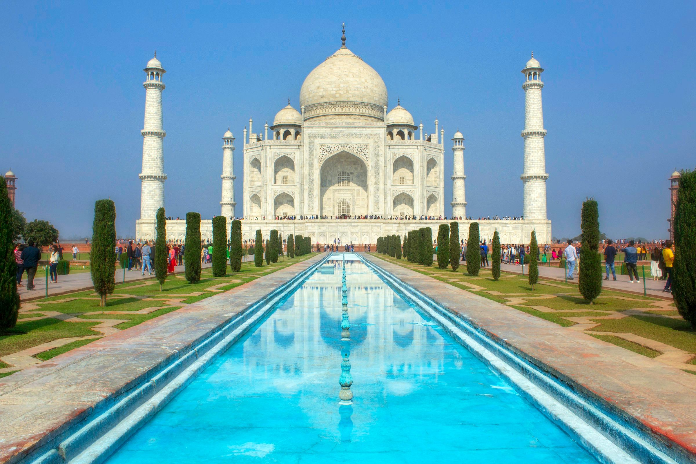 The Taj Mahal reflected in a turquoise garden pool beneath a clear blue sky