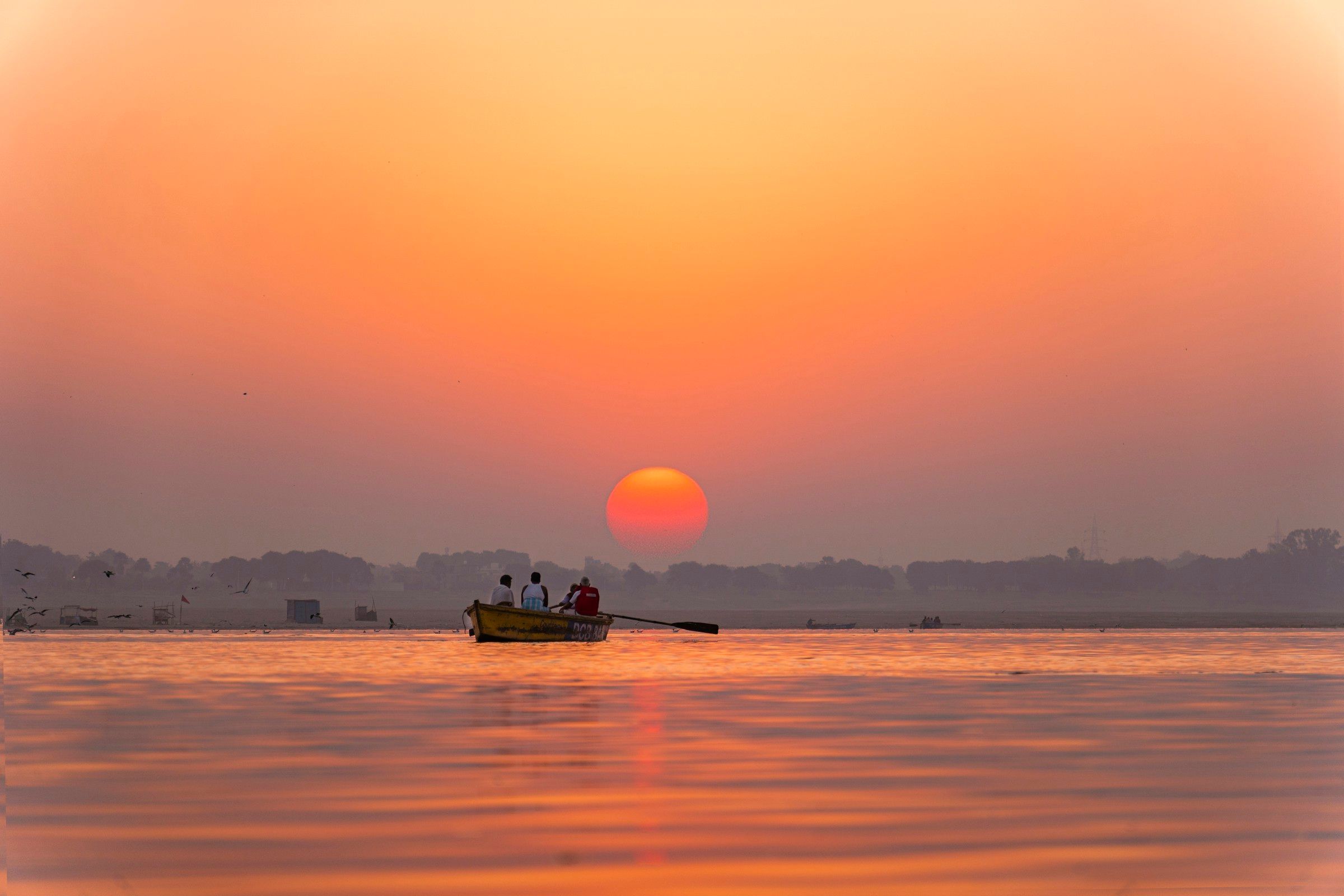 A small boat on the Ganges in Varanasi beneath a golden sunrise