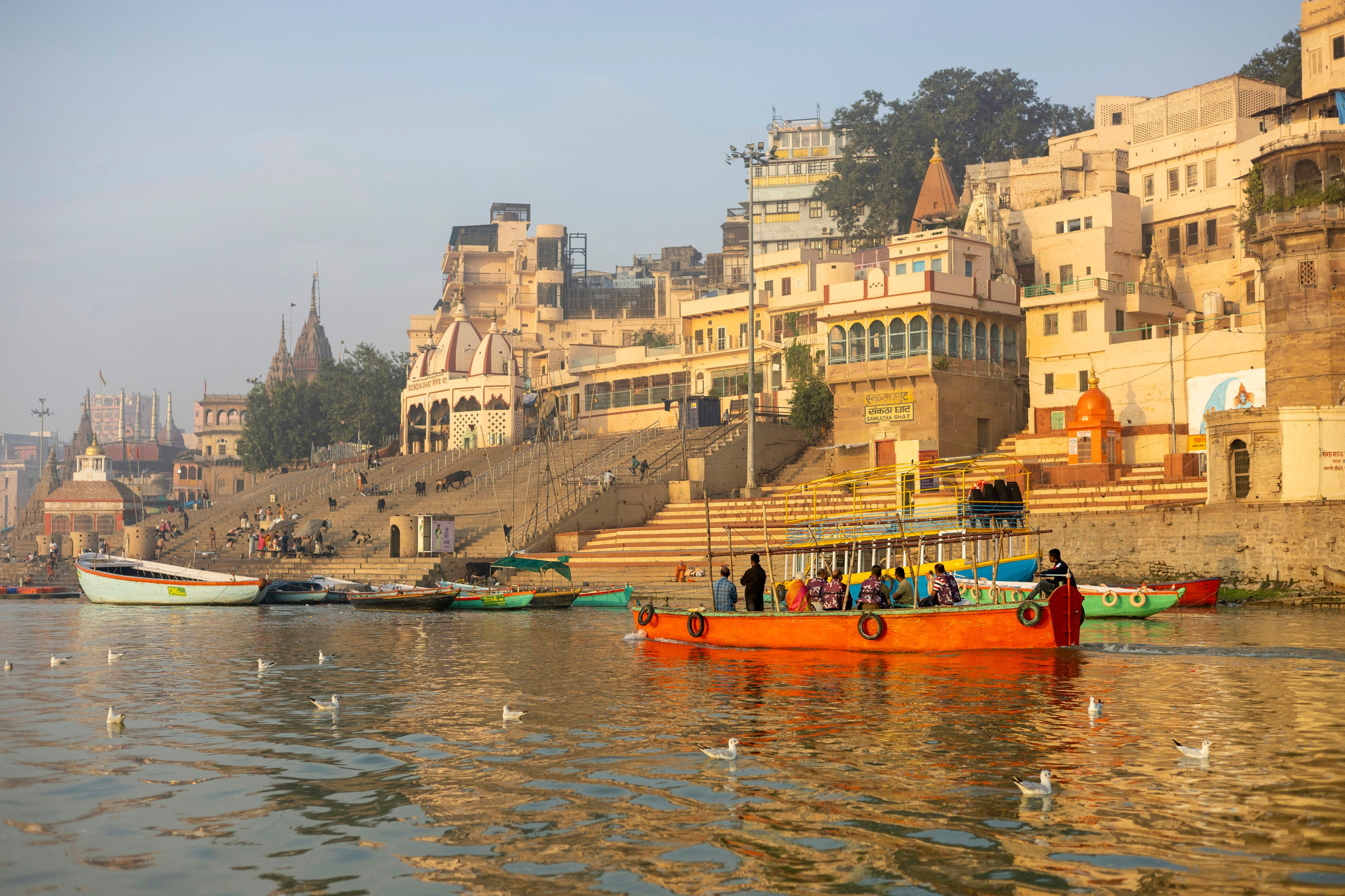 Warm light on Varanasi’s riverfront palaces and ghats, with a wooden boat on the Ganges