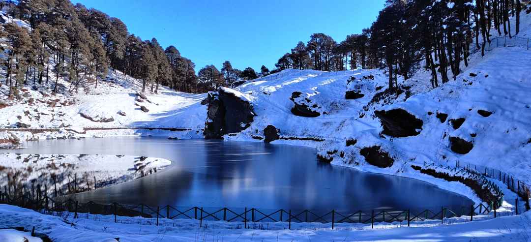 A partly frozen lake surrounded by snow-covered slopes