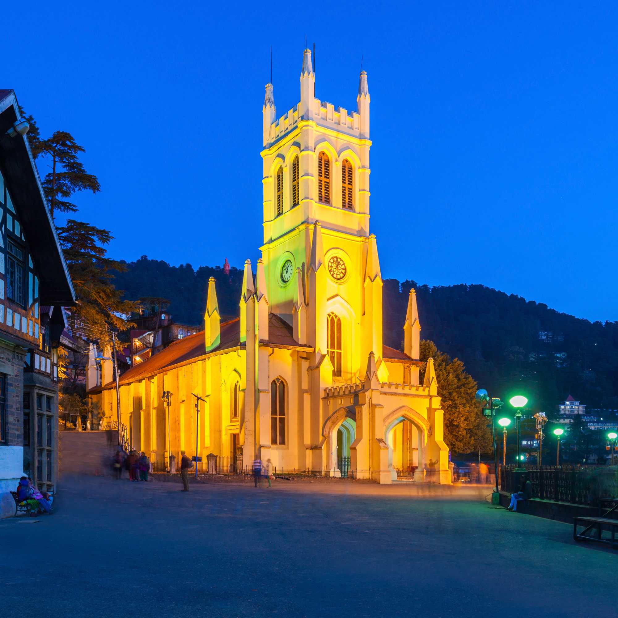 A yellow church tower illuminated against a twilight sky