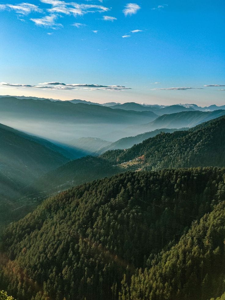 Layered forested mountain ridges above low clouds