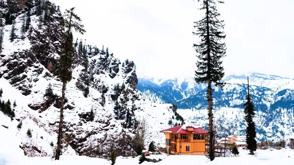 A small temple amid snow-covered trees and mountain views