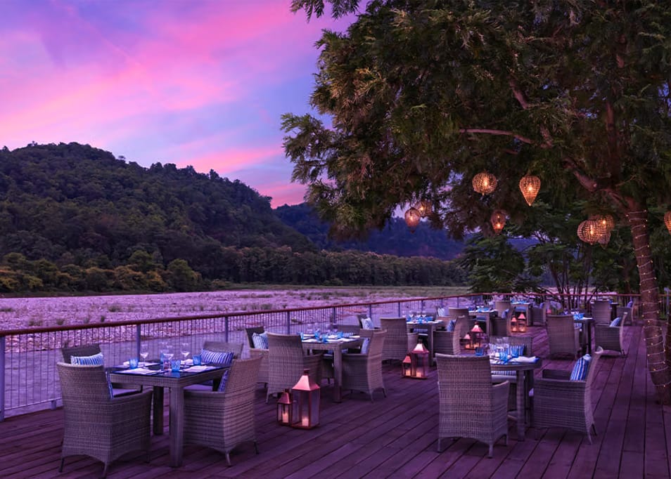 Outdoor dining tables beside a river at dusk