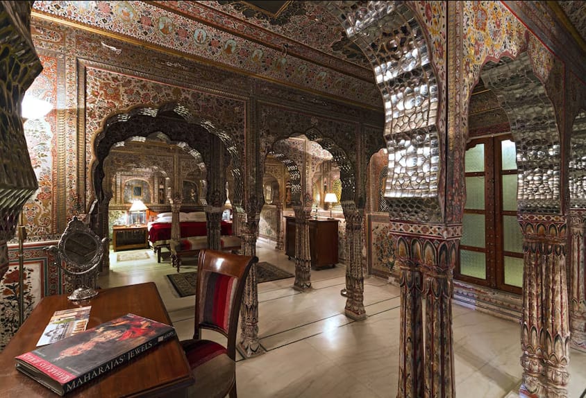 Carved columns and arches framing a furnished palace room