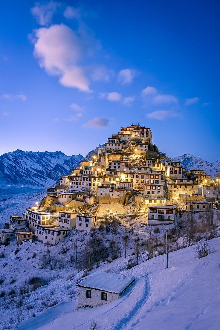 An illuminated monastery on a snowy hill at dusk