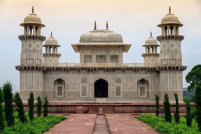 An ornate white marble tomb with four corner towers