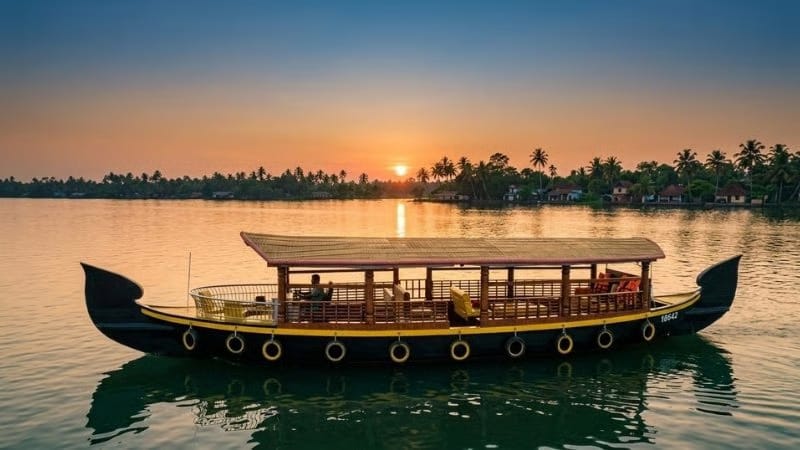 A traditional covered boat on the backwaters at sunset