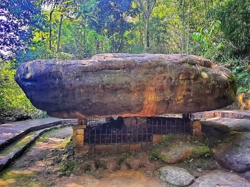 A large balancing rock above a stone base