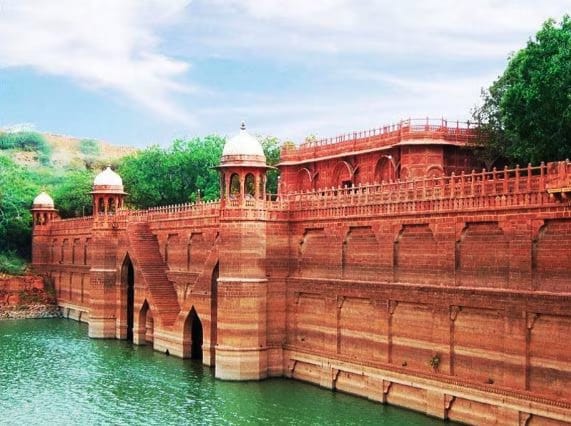Red sandstone palace walls beside a lake