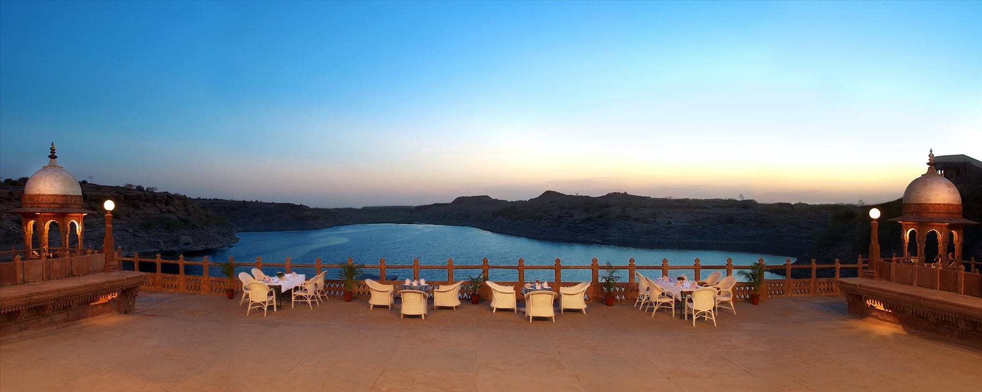 A lakeside terrace set for dining at dusk