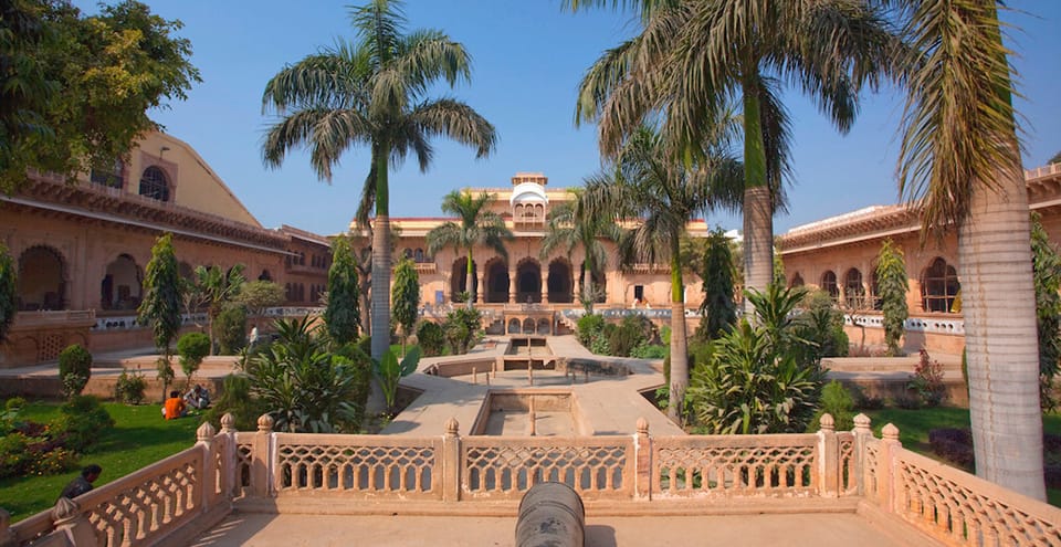 A palm-lined garden and pool outside a heritage building