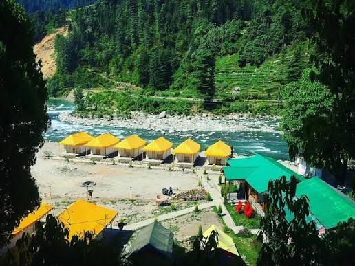 Rows of yellow and green tents beside a mountain river