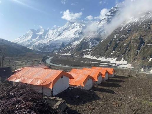 Orange-roofed tent cabins beneath snowy mountains