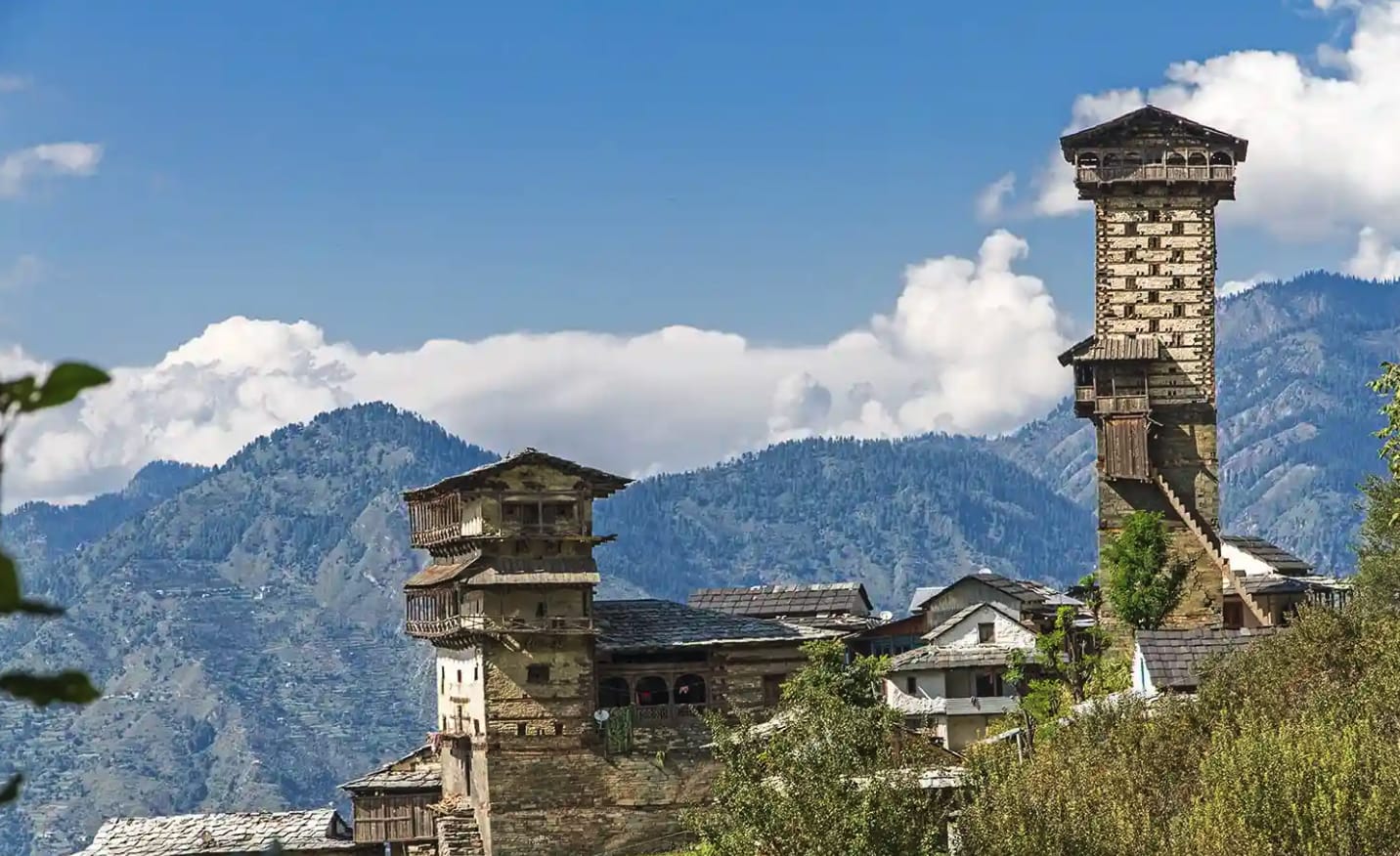 Traditional stone and wooden towers beneath Himalayan peaks