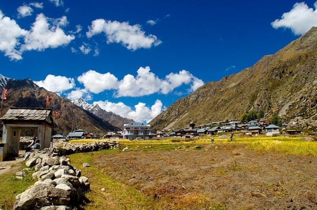 Fields and a village beneath rugged mountain peaks