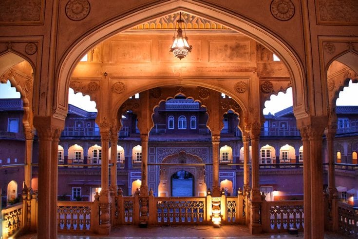 Carved sandstone arches framing an illuminated courtyard