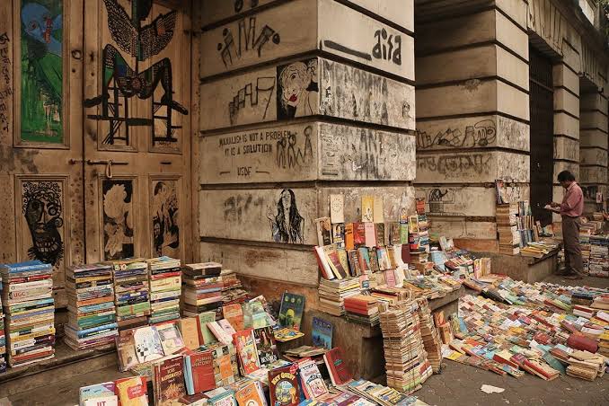 Books stacked around a pillar and along the pavement