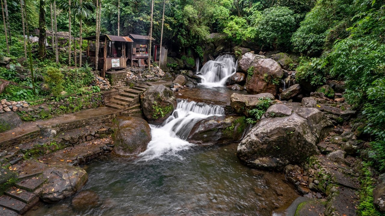 Water cascading over rocks beside a village building
