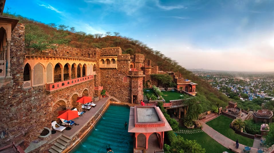 A swimming pool beside stone fort walls and terraces