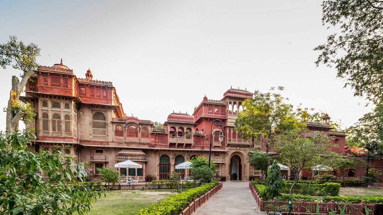 A red stone heritage house surrounded by gardens