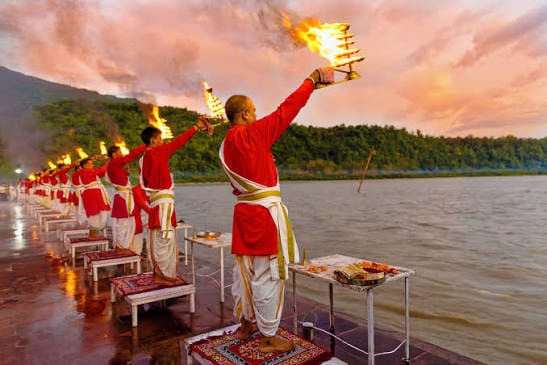 Priests raising lamps during a riverside ceremony