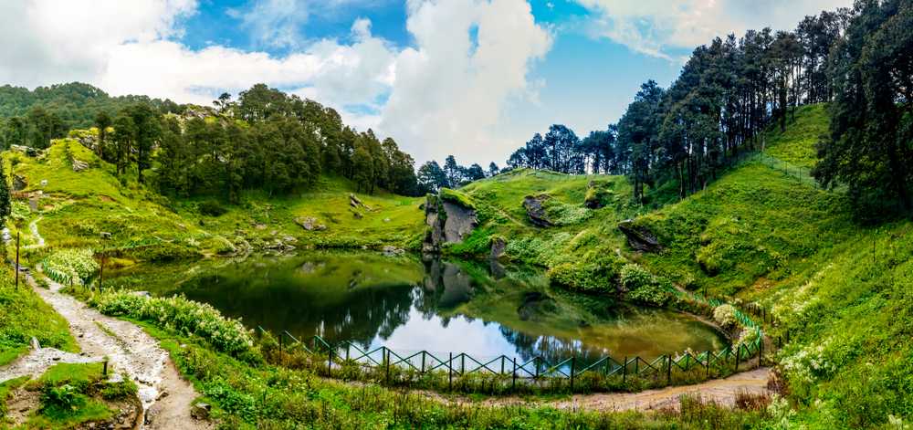 A small lake reflecting grassy slopes and rocky hills
