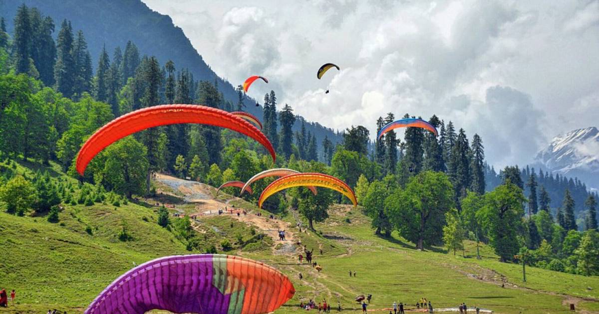 Paragliders launching above a grassy hillside