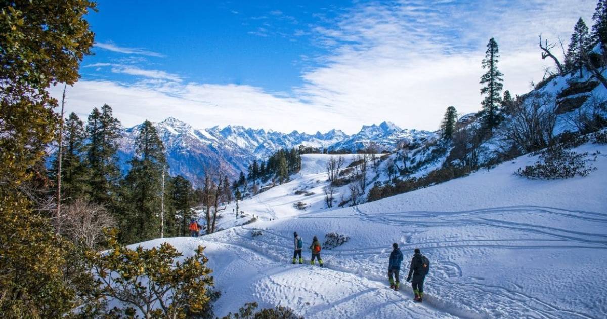 Visitors walking across a snowy valley beneath distant peaks
