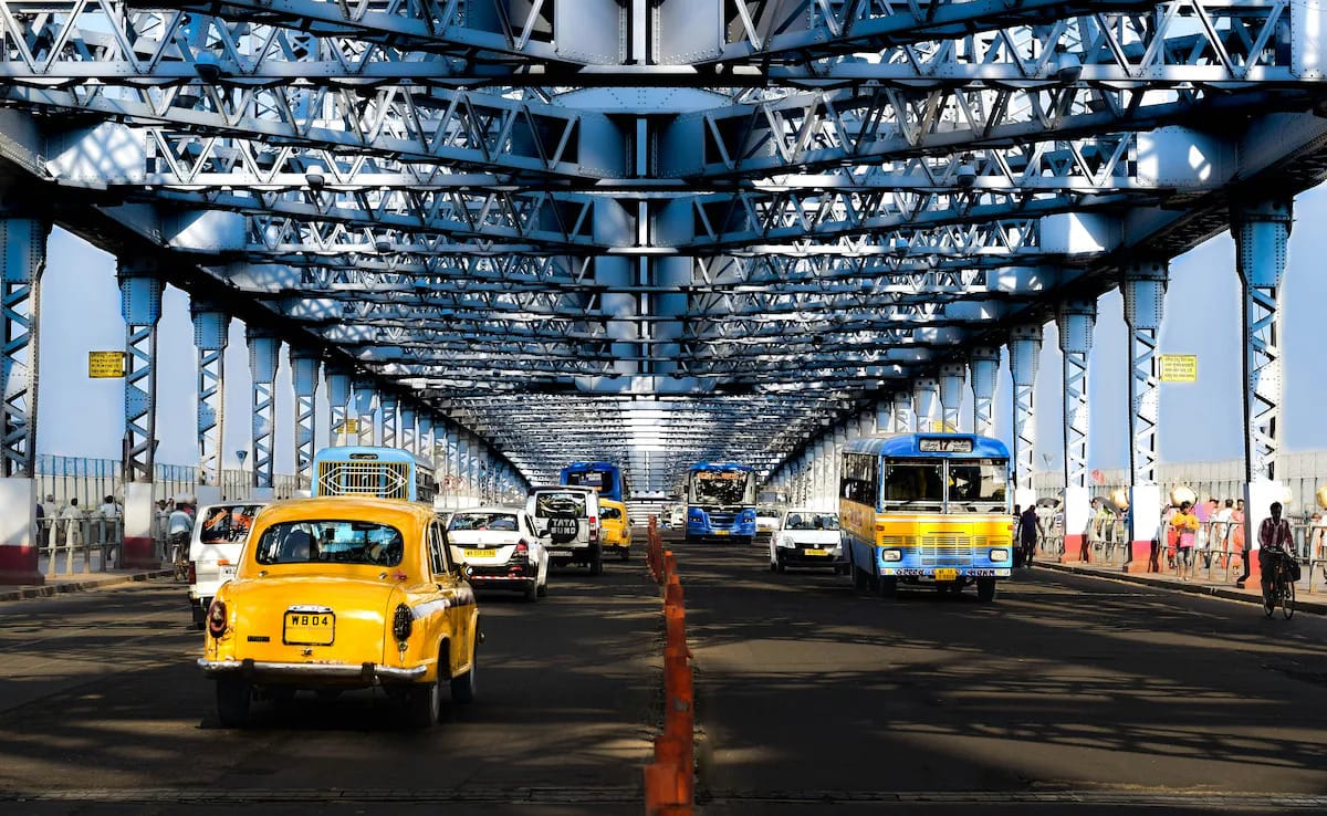 Yellow taxis crossing the steel structure of Howrah Bridge