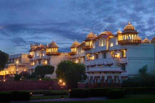 An illuminated palace hotel rising above the lake at dusk