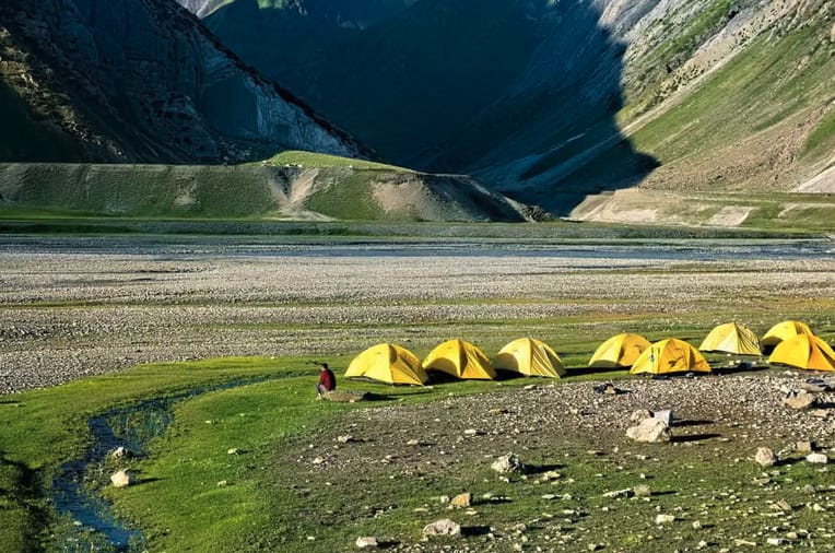 Yellow tents pitched in an open high mountain valley