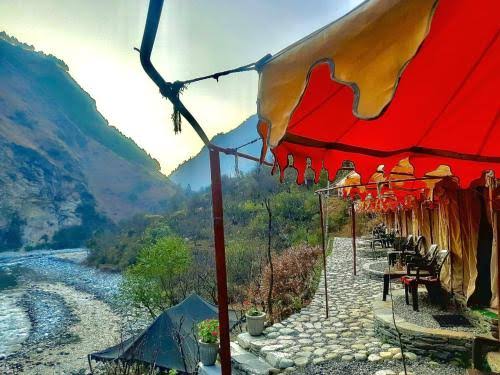 A terrace under a colorful canopy overlooking a mountain river