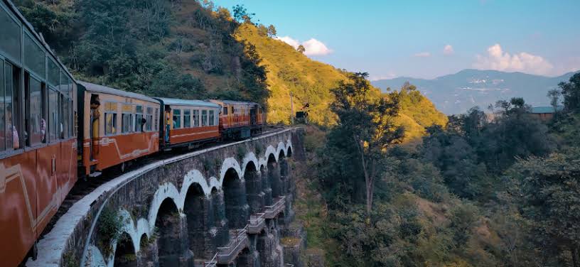 A mountain train crossing a curved stone viaduct
