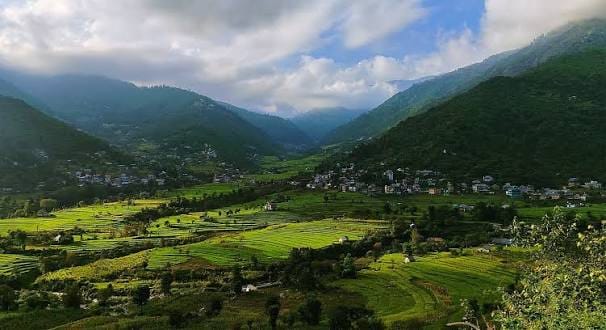 Fields and houses across a broad mountain valley