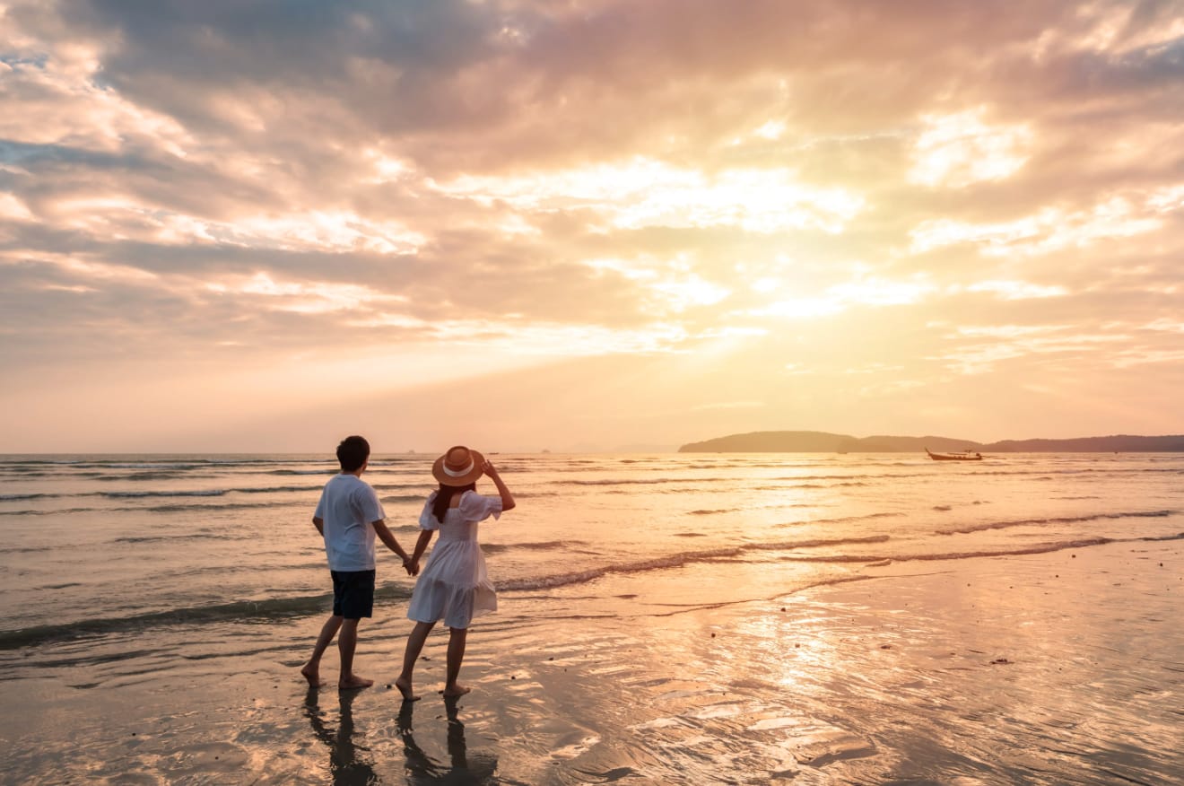 A couple standing at the water's edge at sunset