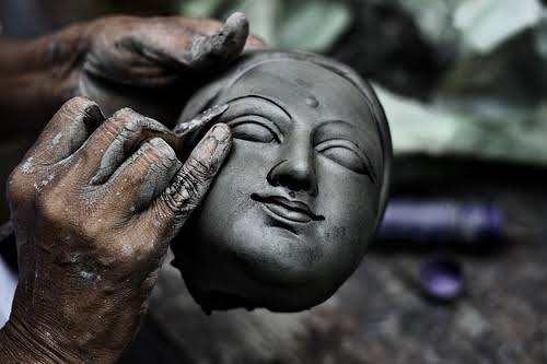 An artisan shaping the face of a clay idol