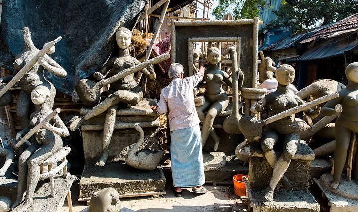 An artisan standing among unfinished clay idols