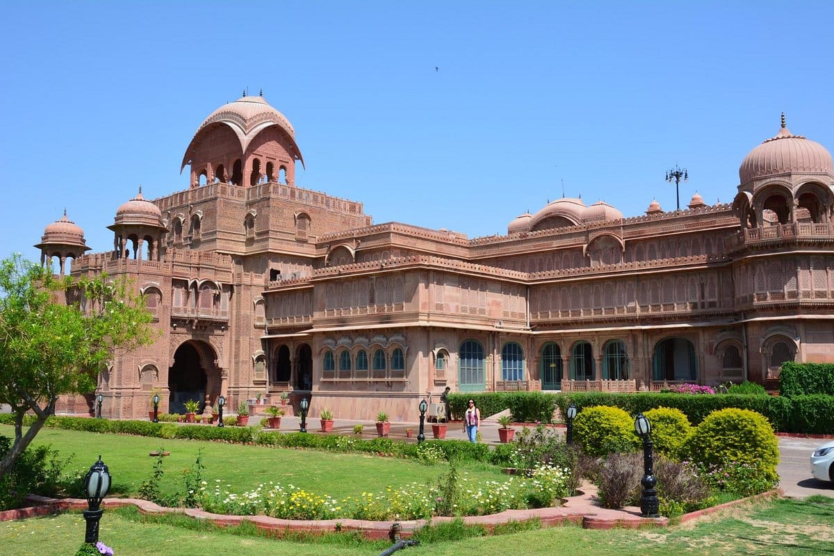 A red sandstone palace building beside green lawns