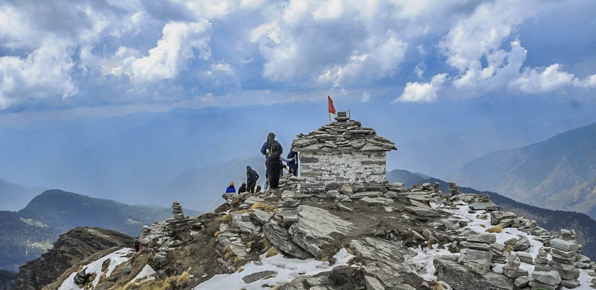 Travelers beside a stone shrine on a rocky summit