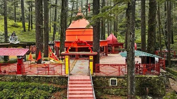 An orange temple surrounded by tall conifers