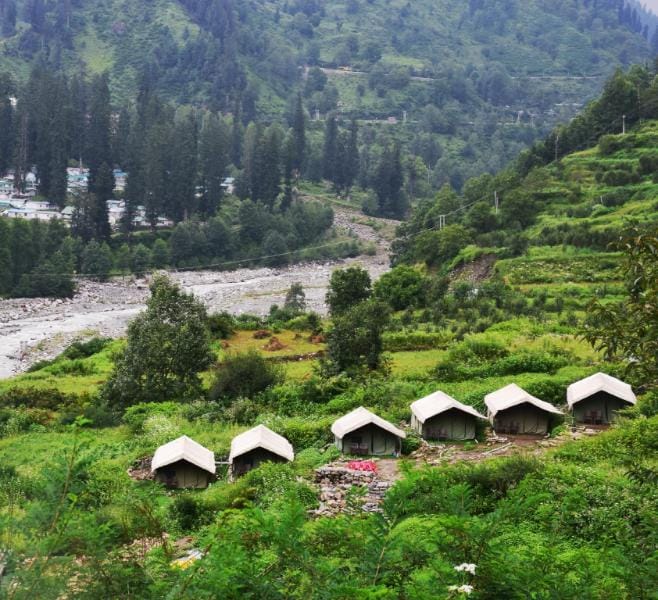 Small tents on a hillside above a wooded river