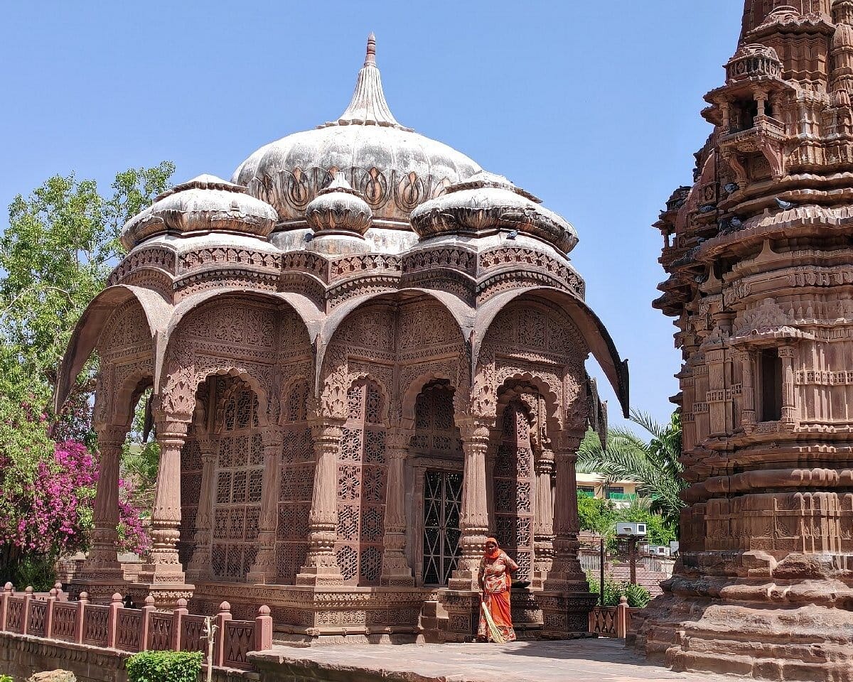 A carved stone pavilion beside a larger historic structure