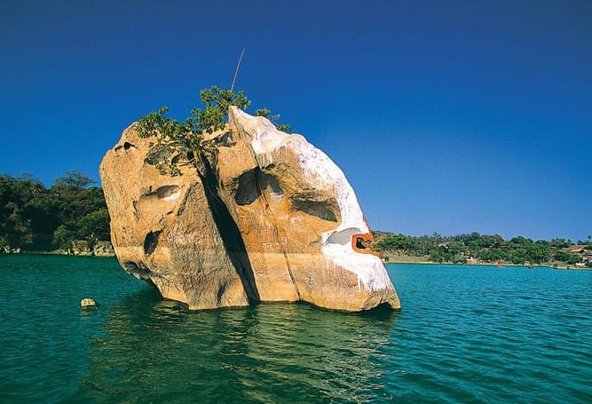 A large rock formation rising from a blue lake
