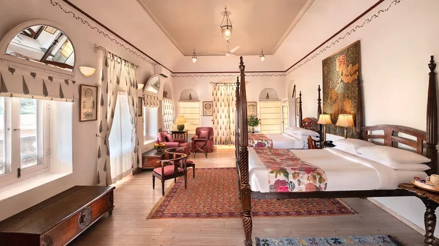 A heritage hotel bedroom with arched windows and wooden furnishings